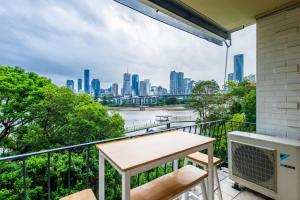 布里斯班Riverside apartment with city & Story Bridge view的市景阳台配有桌椅。