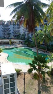 瓜埠ROSSA HOLIDAY APARTMENT的棕榈树和建筑的度假游泳池