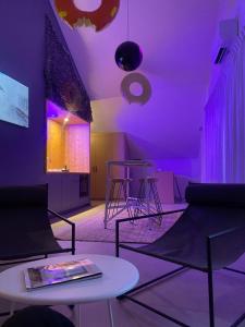 皮耶尔佩尔塞埃Logis Hôtel Altitude et Spa Pierre-Percée的紫色灯和桌椅的房间