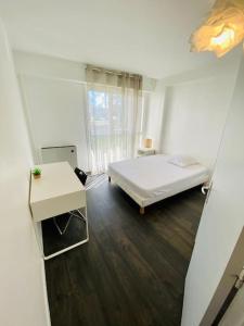 雷于利斯Appartement proche Versailles et sites olympiques的白色卧室配有床和书桌