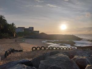 海岸角Orange Beach hostel的海滩上岩石和太阳从海洋上空升起