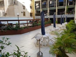 里约热内卢Duplex charmoso - Ótima localização的庭院配有白色椅子和蓝色遮阳伞