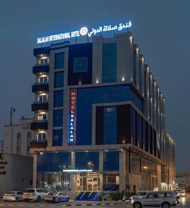 塞拉莱Salalah International Hotel的停车场内停放汽车的大型建筑