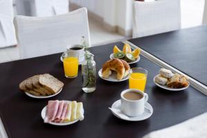 玛德琳港SH Hotel & Spa de Mar Samay Huasi的餐桌上摆放着早餐食品和橙汁盘