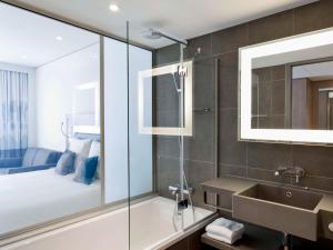 卢加诺诺富特卢加诺天堂酒店 的带淋浴和盥洗盆的浴室以及1张床。