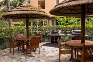 拉海纳阿斯顿玛哈纳卡纳帕利酒店的一个带桌椅和遮阳伞的庭院。