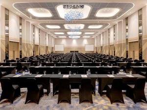 泗水泗水提木尔沙马托诺富特酒店的大房间摆放着桌椅