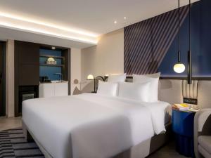 曼谷TRIBE Living Bangkok Sukhumvit 39的一张大白色的床,位于酒店客房内