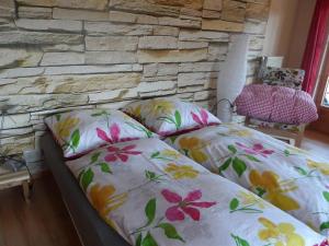 巴特欣德朗Alpakahof Wechs的石墙前的一张带花卉枕头的床