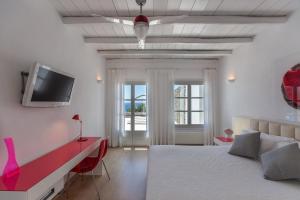 米克诺斯城Fortan 5* villa的卧室配有一张床,墙上配有电视。
