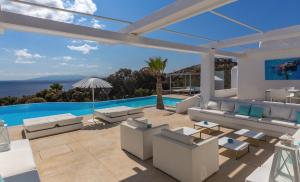 米克诺斯城Fortan 5* villa的一个带白色家具的庭院和一个游泳池