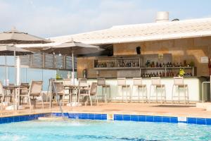 卡塔赫纳卡皮拉德尔玛尔酒店的池畔酒吧配有桌椅