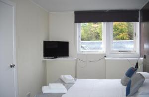阿伯费尔迪The Breadalbane Arms Room Only Hotel的一间卧室设有一张床、一台电视和两个窗户。