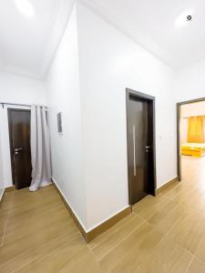 科托努GM IMMO SARL的白色的客房设有三扇门,铺有木地板
