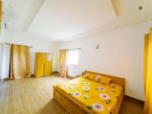 科托努GM IMMO SARL的一间卧室配有一张带黄色床罩的鲜花床