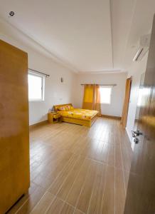 科托努GM IMMO SARL的一间大客房,配有一张床,铺有木地板