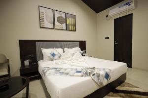 KevadiaVindhyachal Resort的一间卧室配有一张带白色床单和一张桌子的床。