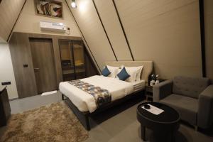 KevadiaVindhyachal Resort的一间卧室配有一张床、一张沙发和一把椅子
