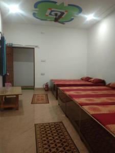 巴德里纳特Badrinath Dharmshala by Prithvi Yatra Hotel的一间设有几张床的客房,位于一间铺有地毯的房间