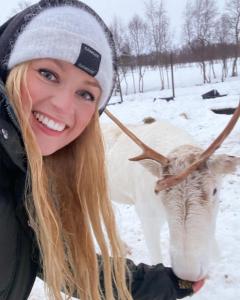 BøRingstad Resort的雪中一头母牛旁边一个女人微笑着
