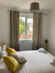 伦敦Gresham House - London Excel的一间卧室配有一张带黄色枕头的床和一扇窗户