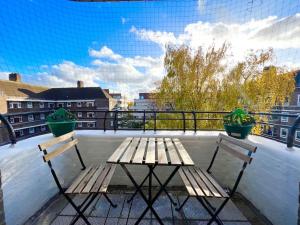 伦敦2 Bed- Belsize Park的阳台上配有一张木桌和两把椅子