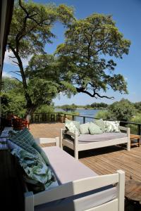 利文斯顿Zambezi Dusk的一个带两张沙发、一棵树和水的甲板