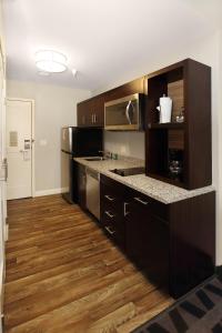 格罗夫城默瑟县格罗夫城/奥特莱斯万豪广场套房酒店的厨房铺有木地板,配有黑色橱柜。