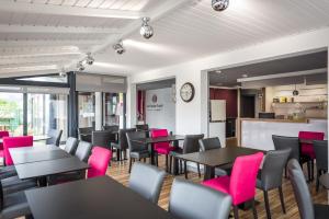 韦尔图Logis hôtel restaurant la Haute Forêt的配有桌椅和粉色椅子的餐厅