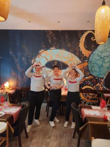 贝济耶新城恩梵特斯特力宝酒店的三名妇女站在一家餐馆壁画前面