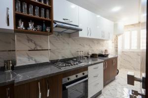 丹吉尔IMMOKA的厨房配有白色橱柜和炉灶烤箱。