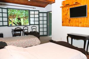 巴纳纳尔Fazenda Dos Coqueiros-Bananal-SP的一间卧室配有两张床和一台平面电视