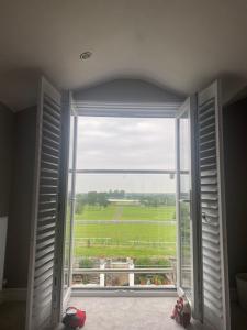 安特里Aintree Grand National Home的享有绿色田野景致的开放式窗户