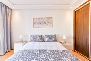 拉巴特Appartement Charmant & Cozy - Centre ville de Rabat的白色卧室配有一张大床和两盏灯。