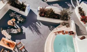 伊亚Sun Angelos Oia - Luxury Cave Suites的游泳池的顶部景色,有两名女性躺在浴缸上