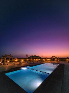 梅尔祖卡Berber Palace Merzouga的夜间游泳池,灯光照亮
