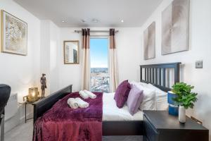 斯劳LUX CONDO for 5 Slough Elizabeth line free parking的一间卧室配有一张带紫色床单的床和窗户。
