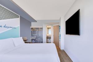 马萨特兰One Mazatlán的卧室配有白色的床和平面电视。