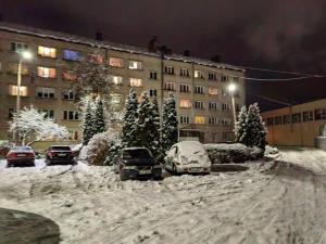 奥格雷Apartamenti dzīvoklis Ogre.的一条雪覆盖的街道,在建筑物前停放汽车
