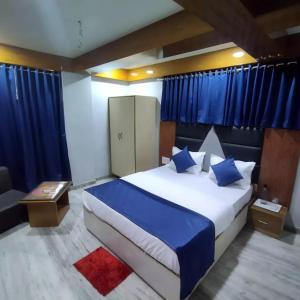 艾哈迈达巴德HOTEL SHREE RADHE的一间卧室配有一张带蓝色窗帘的大床