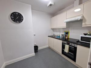 伦敦Eldon Chambers Pod 4 by City Living London的厨房配有白色橱柜和墙上的时钟