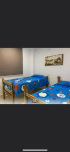 圣玛尔塔Hostal Los Arhuacos的一间卧室配有两张带蓝色棉被的床