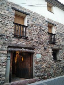 Pina de MontolgraoCasa la Cisterna的一座古老的石头建筑,设有木门和阳台