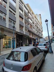 维戈Apartamento Turístico Menéndez Pelayo -Vigo的停在大楼前的街道上的汽车