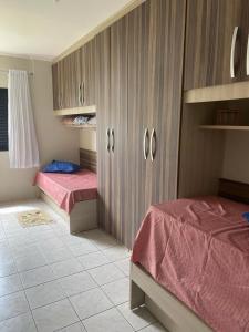 蒙加瓜Apartamento beira mar Centro da cidade WiFi grátis的一间卧室设有两张床和木制橱柜。