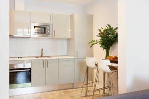 巴塞罗那Beautiful 4bd 4ba apartment in Eixample District的厨房配有白色橱柜、水槽和凳子