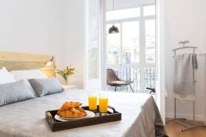 巴塞罗那Beautiful 4bd 4ba apartment in Eixample District的床上的托盘食物,配上两杯橙汁