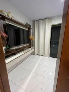 伊瓜苏Casa c/ piscina e edícula的客厅配有大电视和白色瓷砖地板。