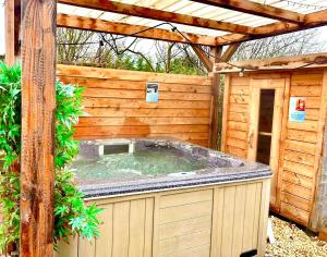 VijfhuizenWellness bungalow with jacuzzi &sauna&private garden near Amsterdam的一座带凉亭的木质建筑中的热水浴池