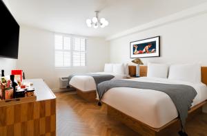 洛杉矶Short Stories Hotel的配有白色墙壁和木地板的客房内的两张床